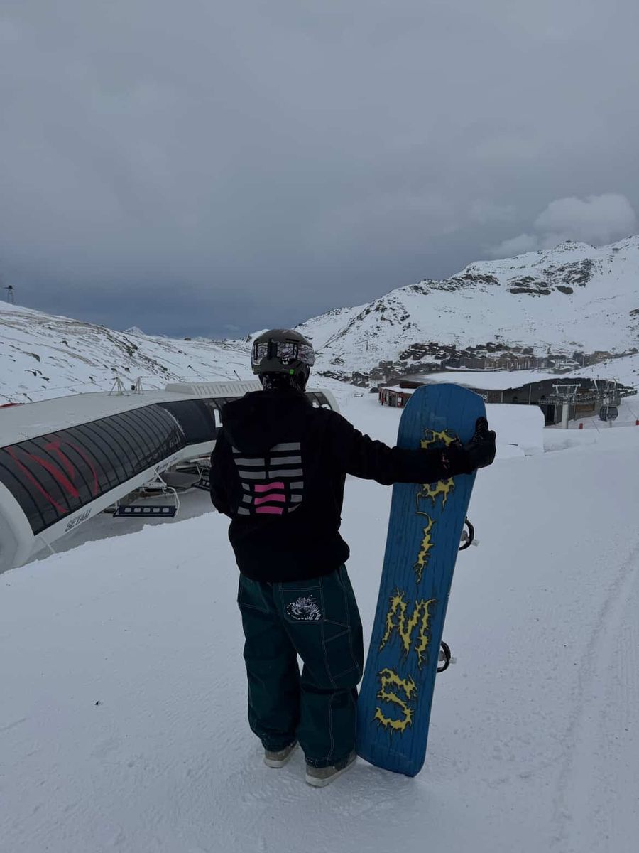 A rider with a blue snowboard at the top of a lift
