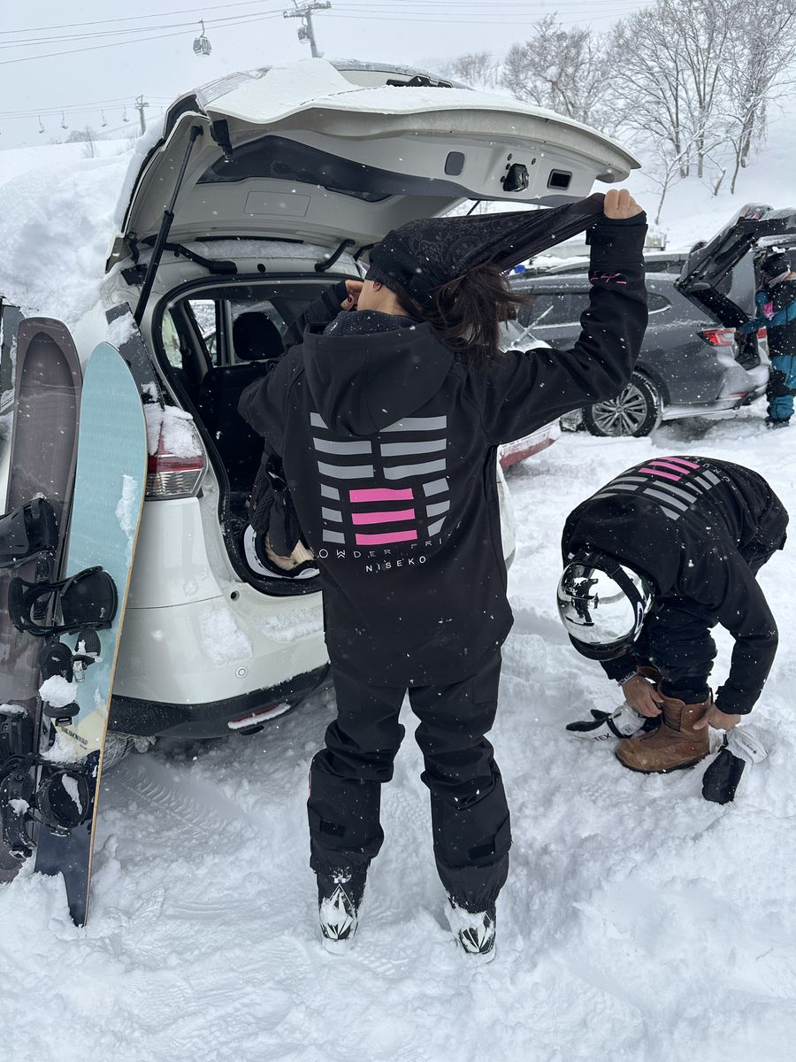 Riders gearing up by the car in falling snow