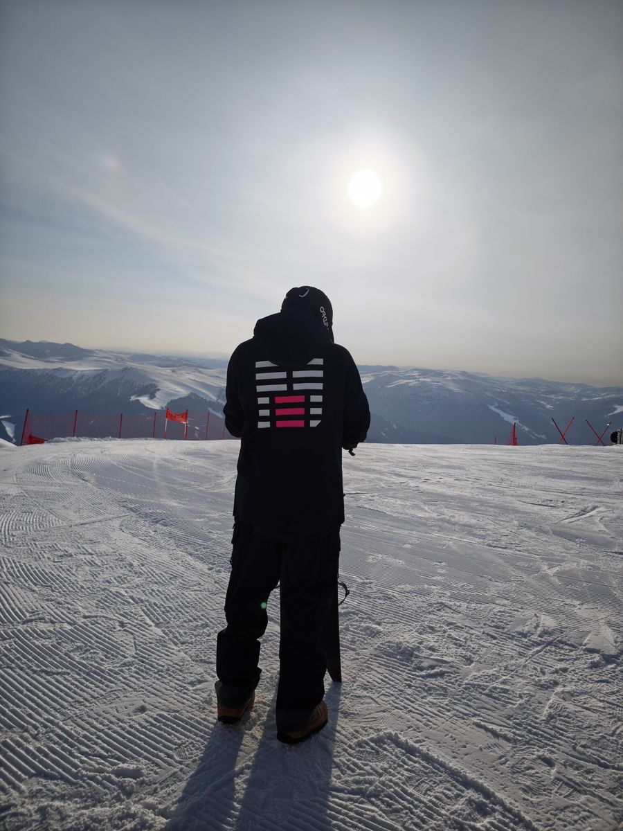 A rider facing the sun at the top of a run
