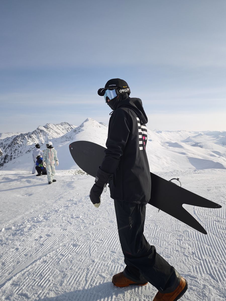 A rider carrying a swallowtail board along a ridge